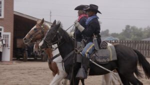 Two performers ride horses in Cavalry uniforms to share the story of the Buffalo Soldiers.