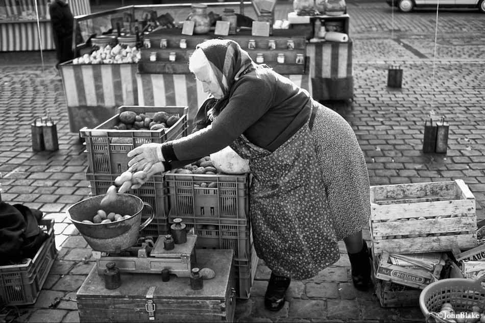 Women sets out vegetables at a market in a black and white image.