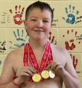 Caleb Thompson with his gold medals from swimming.