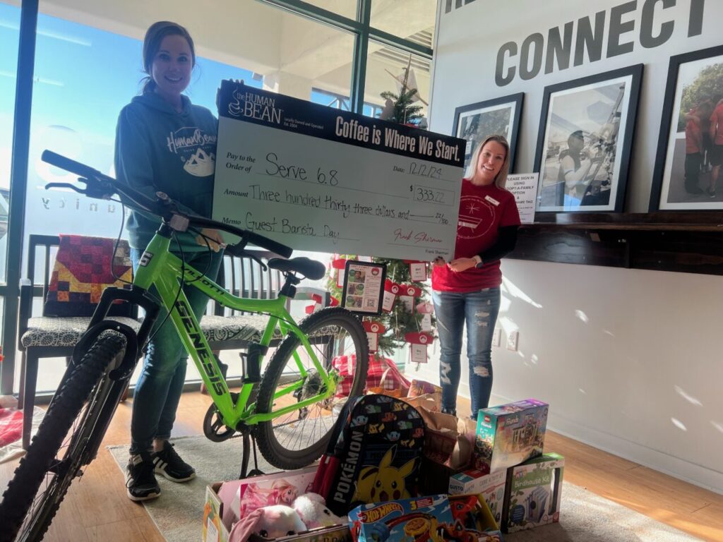 A check for $333.22 and toys—including a new bike—being presented to the nonprofit Serve 6.8. 