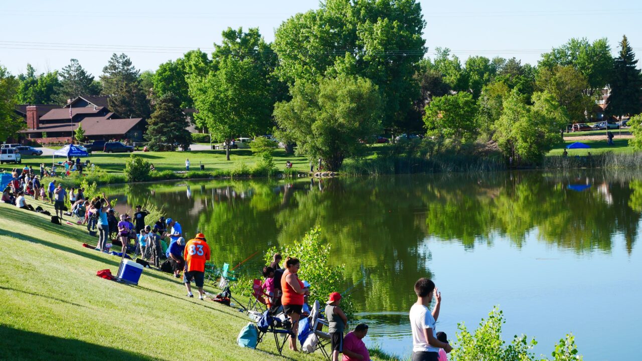 Adults and youth surround Sanborn Lake for the Annual Fishing Derby in Greeley.